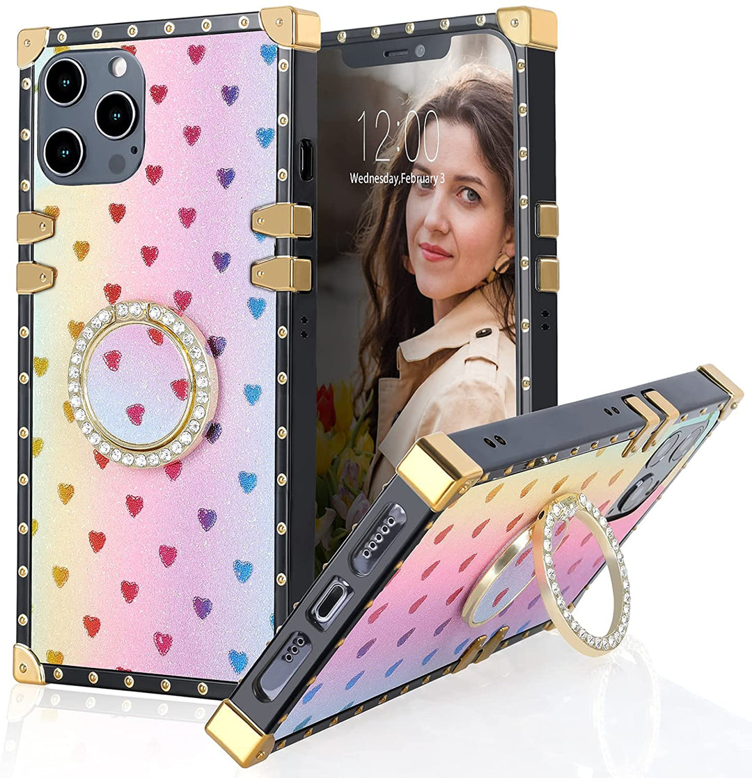 A box-shaped, TPU, iPhone 12 Pro Max case, with gold corner bumpers and gold rivets on its black trim. The case’s back is designed rainbow-colored, with rainbow hearts, and glitter. A gold trim ring, with diamond studs, doubles as a handle and kickstand for the case. #color_rainbow-glittery-hearts