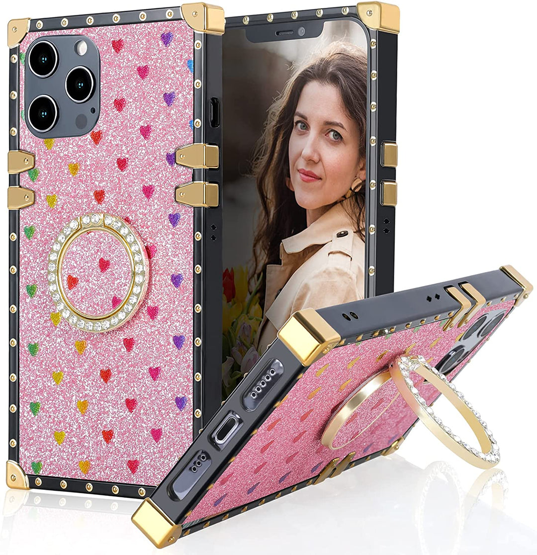 A box-shaped, TPU, iPhone 12 Pro Max case, with gold corner bumpers and gold rivets on its black trim. The case’s back is designed pink, with rainbow hearts, and glitter. A gold trim ring, with diamond studs, doubles as a handle and kickstand for the case. #color_pink-glittery-hearts