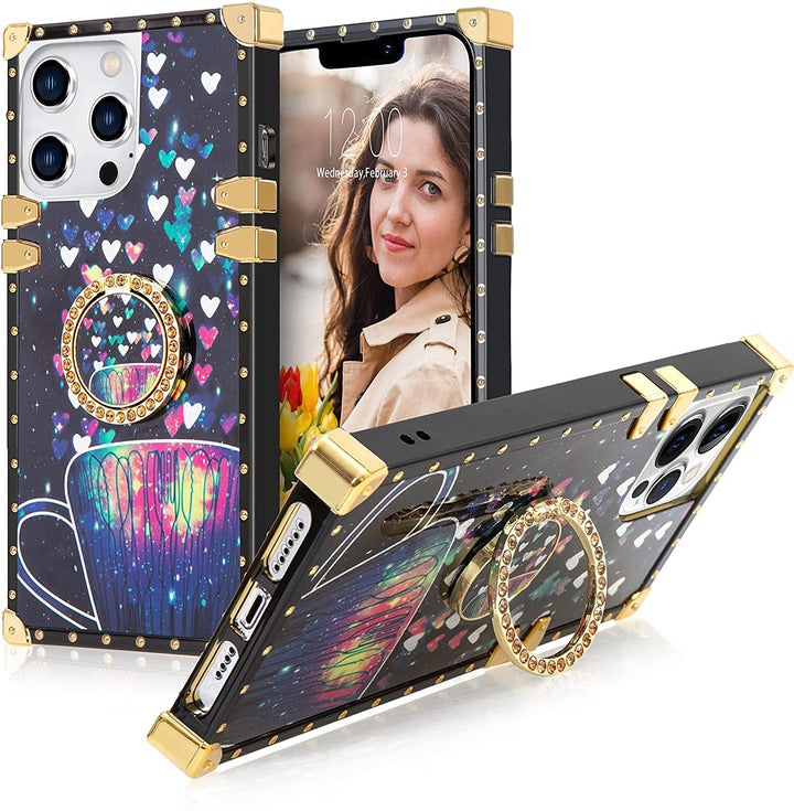 A box-shaped TPU case with gold corner bumpers and gold rivets on its black borders. The case’s back design has small hearts and a coffee mug in a black-blue-purple cosmic backdrop. The case also has a gold ring handle that doubles as a holder and kickstand. #color_holo-black-heart-lantern